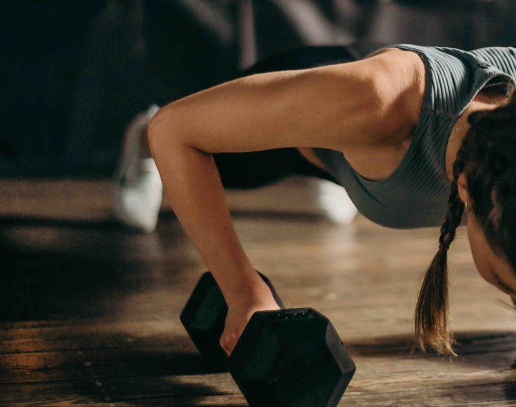 A woman doing a plank on a dumbbell to symbolize the importance of exercise in weight loss